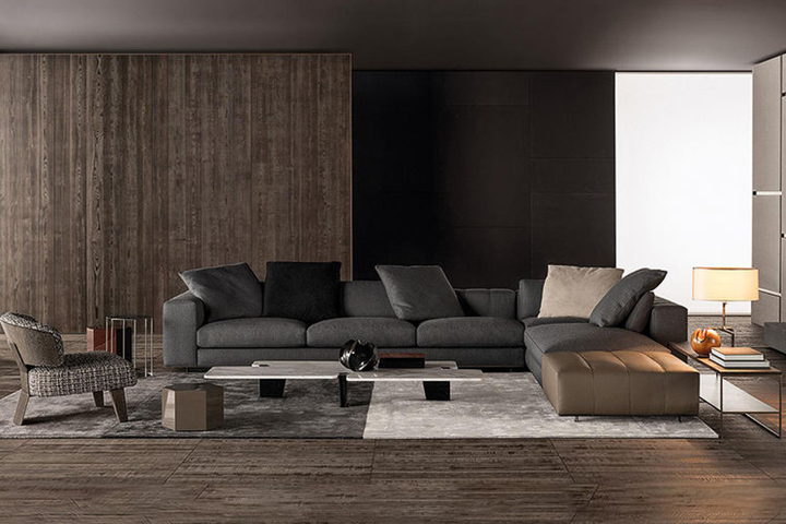The Alessia sofa — a low, deep-seated modular sofa in charcoal wool with a bronze-framed side table