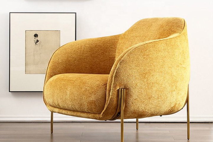The Chiara chair — a sculpted armchair in saffron velvet on tapered brass legs