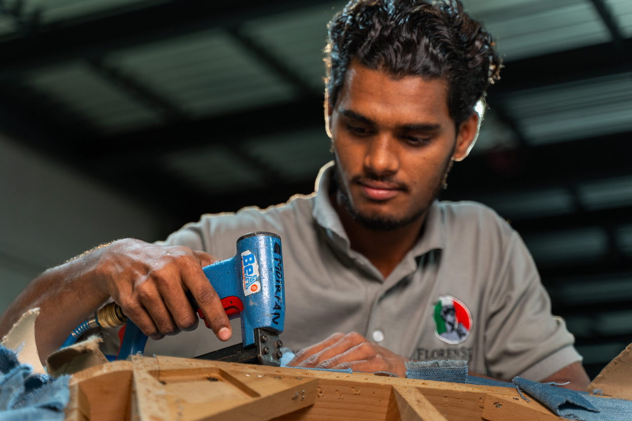 A craftsman fixing a joint on a solid timber furniture frame during final assembly