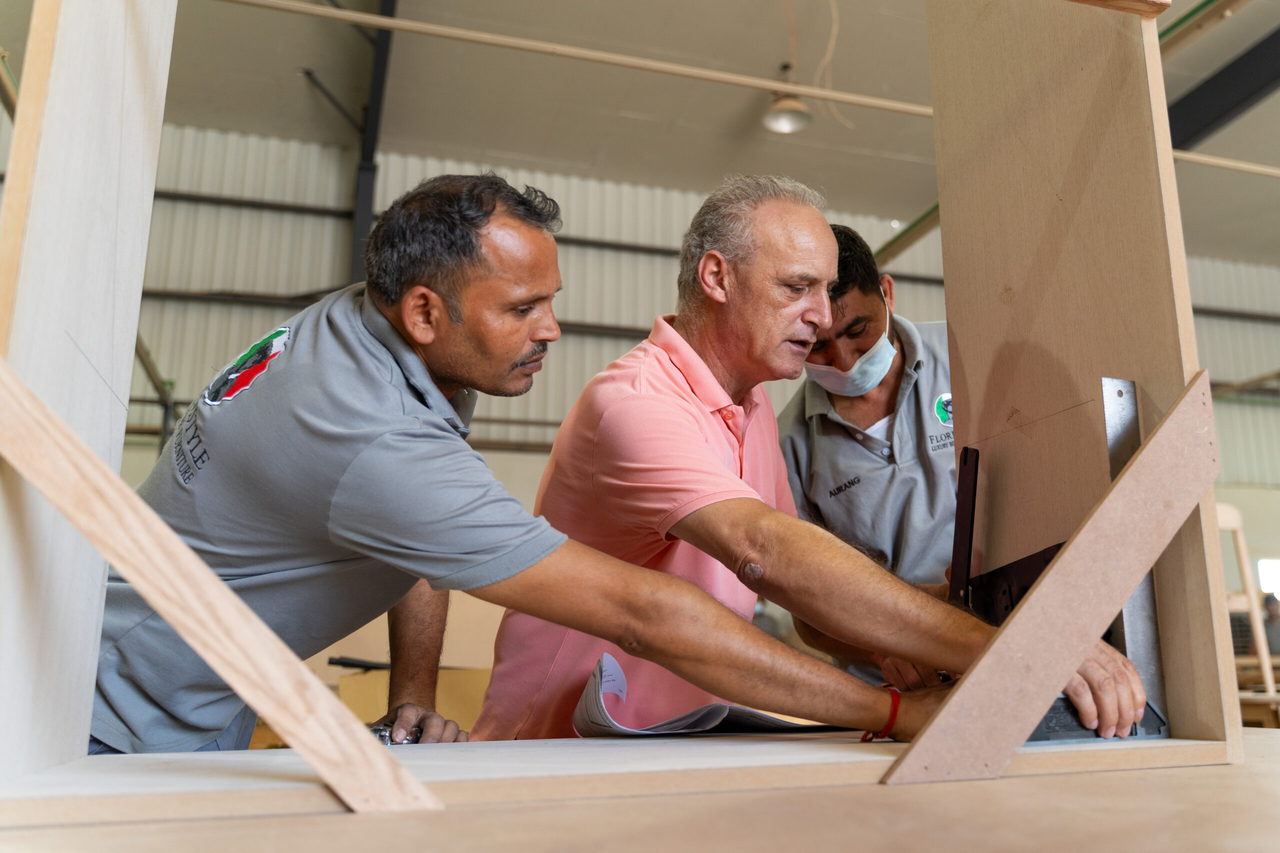 The FlorenStyle team reviewing a veneered panel together on the workshop floor