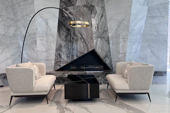 A lounge with a book-matched marble fireplace wall, twin lounge chairs and an arched floor lamp
