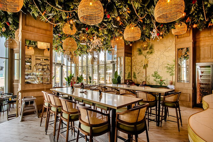 A garden-themed restaurant with a suspended planted ceiling, rattan pendants and bespoke timber seating
