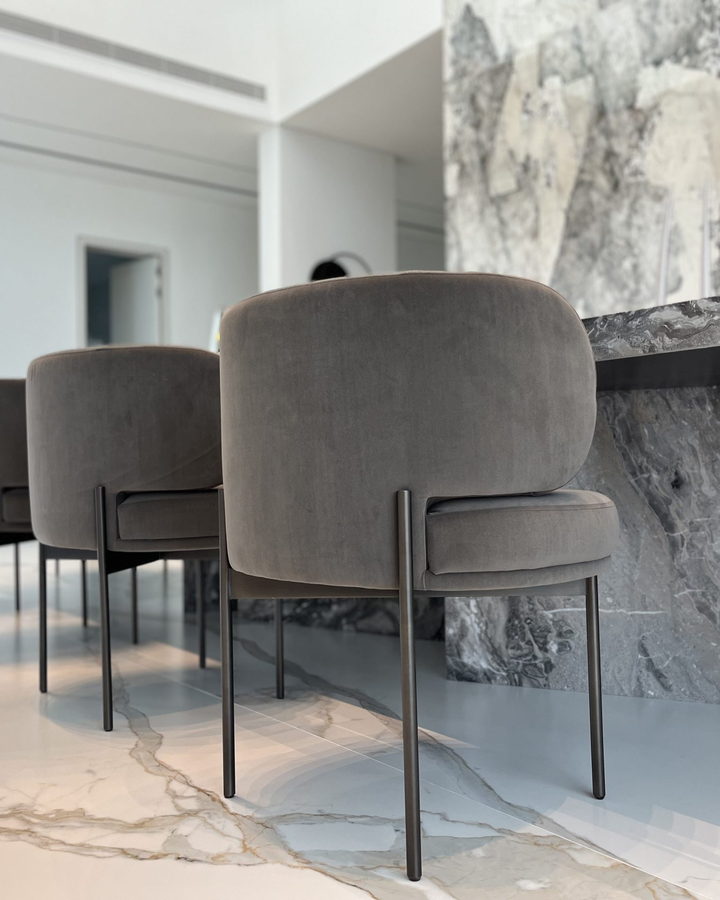 Bespoke upholstered counter stools lined against a dramatic grey marble island
