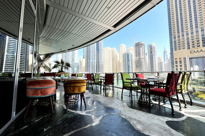 A rooftop restaurant with curved banquette seating and floor-to-ceiling windows onto the city skyline